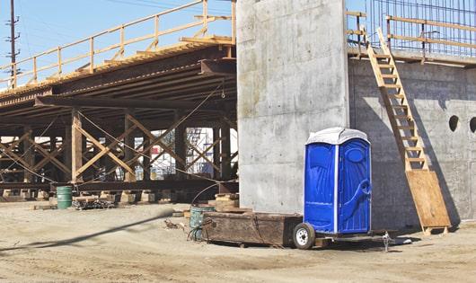 a row of blue portable toilets set up on a work site